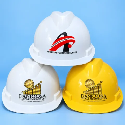 Safety Helmet Branding Three branded safety hard hats, two white and one yellow, stacked on a blue background displaying custom printed company logos on the front shells.